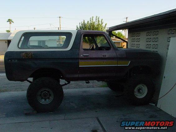 Lifted 1979 Ford Bronco side view, dark red and white with yellow stripe