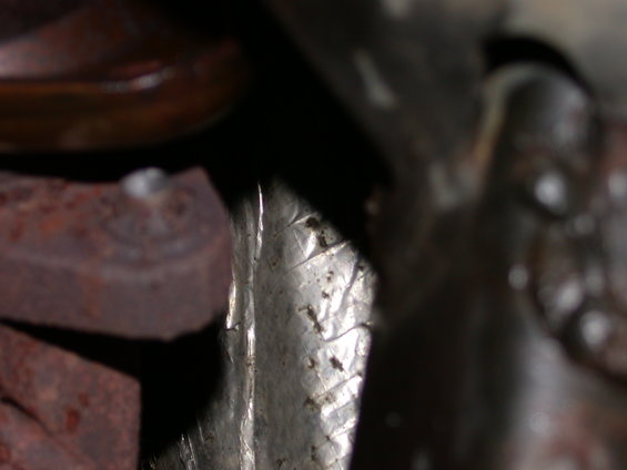Close-up of rusted exhaust manifold and reflective heat shield