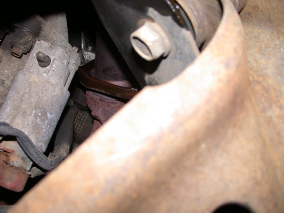 Close-up of a rusted exhaust manifold gasket and surrounding metal components