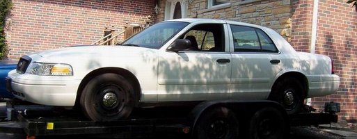 White Ford Crown Victoria on a trailer, side view
