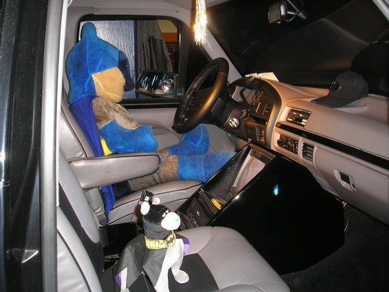Batman plush toy in driver's seat of a truck, with a dog plush toy on the passenger seat