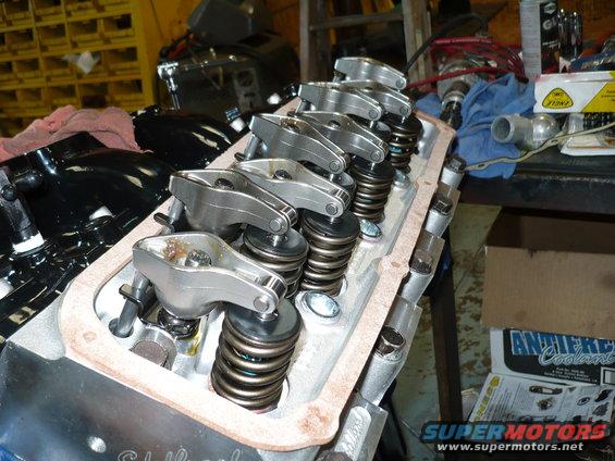 Close-up of engine valve train with rocker arms and springs. A box labeled 'Antifreeze Coolant' is visible in the background