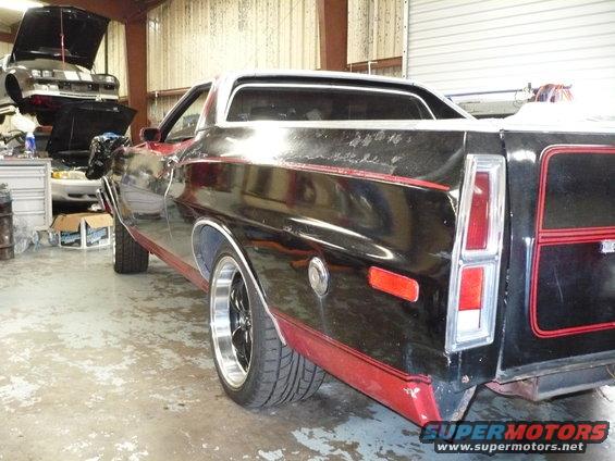 Black 1972 Ford Ranchero with red trim, rear quarter view, showing damage and aftermarket wheels