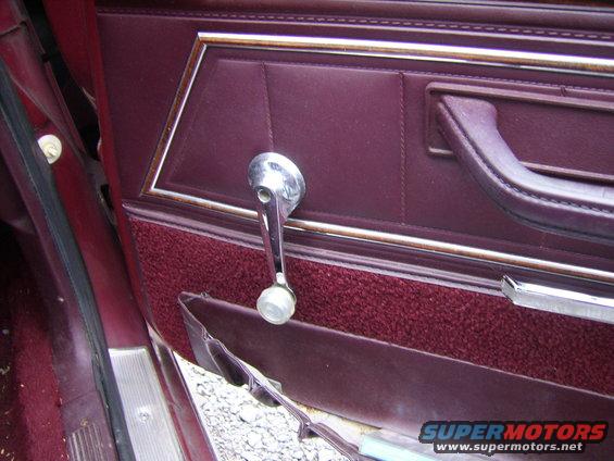 Maroon car interior door panel with chrome window crank and fabric trim. Water damage is visible