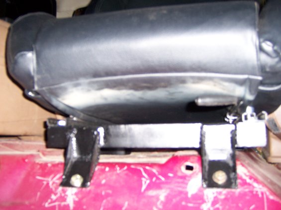Black leather seat base on black metal brackets bolted to a red surface