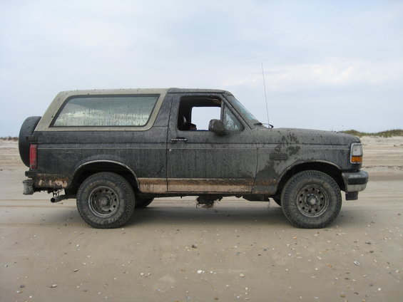 Mud-covered Ford Bronco parked on a sandy beach