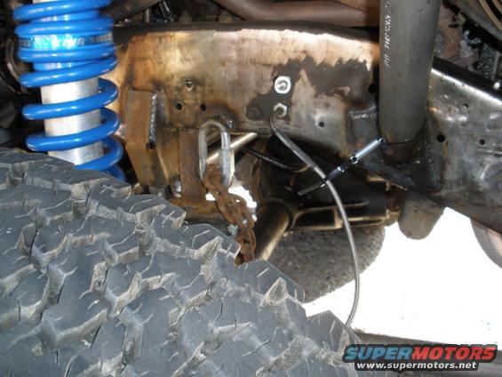 Off-road tire and blue coilover shock assembly on a heavily modified vehicle frame