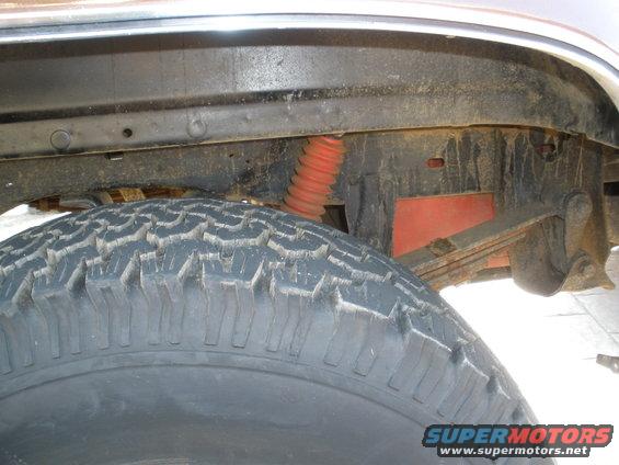 Tire and suspension components of a vehicle, with red shock absorber and leaf springs visible