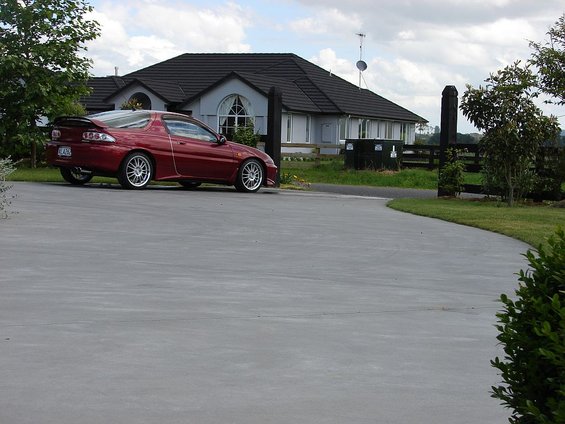 Red 1993 Mazda MX-3 parked on a driveway in front of a house