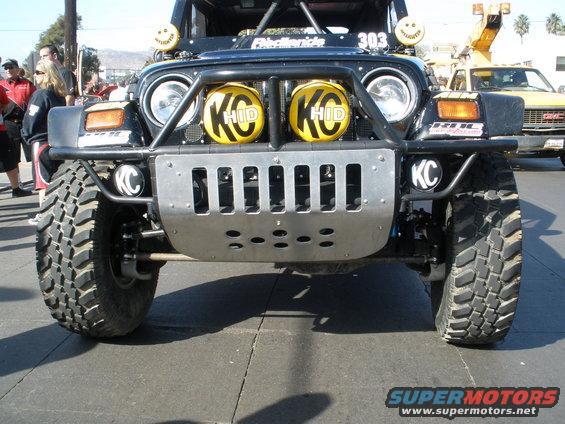 Front view of a modified Jeep Wrangler with KC HID lights and a skid plate
