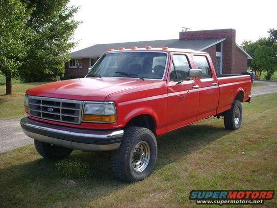 Red 1992 Ford F-350 pickup truck, four-door cab, parked on grass in front of a house