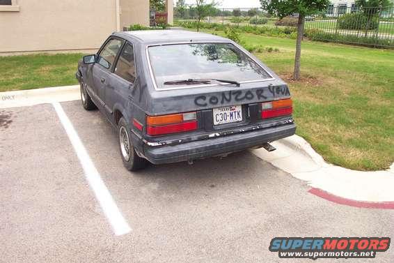 Dark gray 1983 Honda Accord hatchback parked in a lot, rear view, with graffiti on the trunk