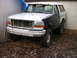 1995 Ford Bronco - A two-tone Ford Bronco sits in front of a garage with its grille removed.
