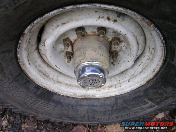 Close-up of a vehicle's wheel hub with a chrome cap and lug nuts, next to a tire with 'PRO' visible