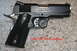 2007 Nissan Titan - A black Colt 1991A1 Compact pistol with textured grips is shown on a speckled surface.