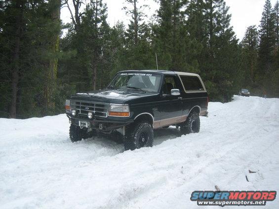 1995 Ford Bronco driving in snow with another vehicle in the background