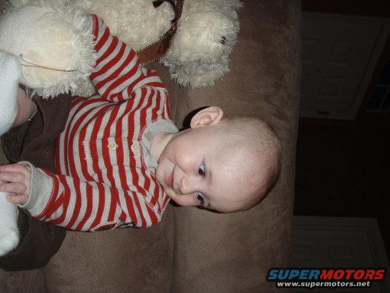 Baby lying on a couch next to a teddy bear