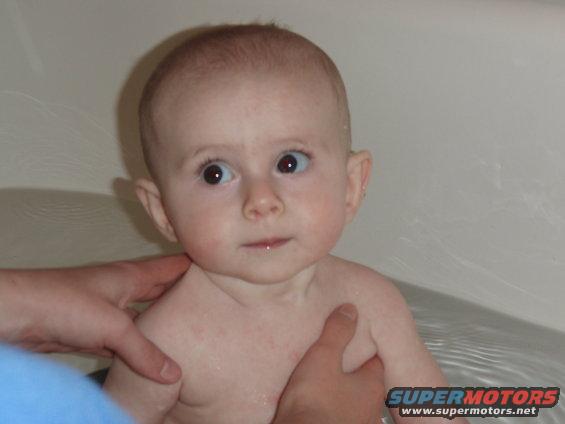 Baby in bathtub being held by hands