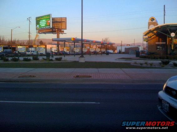Gas station with covered pumps and a large billboard in the background under a clear sky