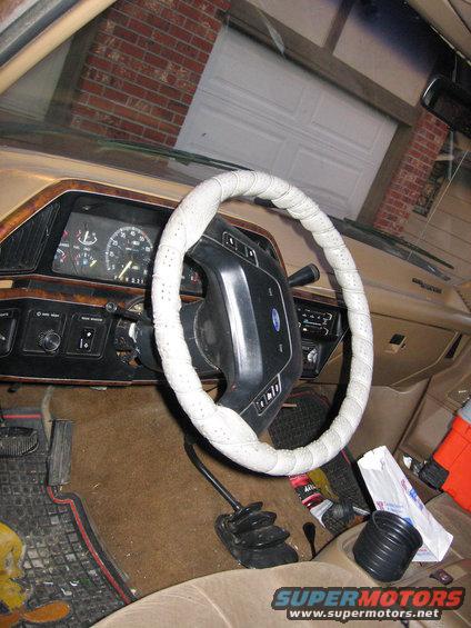 Interior shot of a truck's dashboard, steering wheel, and gear shifter. The steering wheel has a white cover