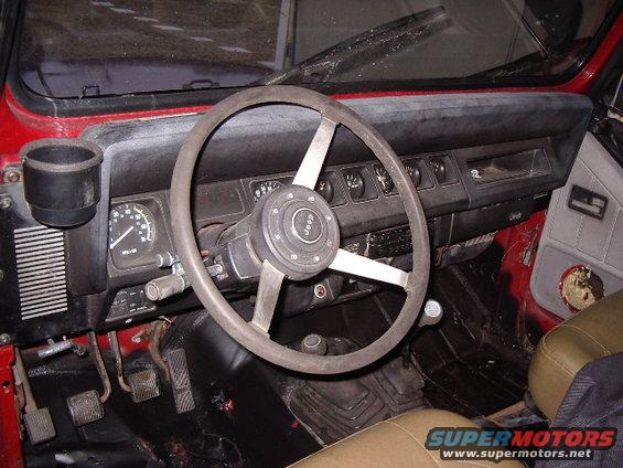 1987 Jeep YJ interior showing dashboard, steering wheel with Jeep logo, and floor pedals