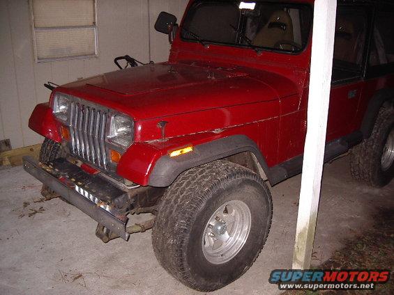 Red 1987 Jeep YJ with chrome grille and aftermarket wheels parked indoors