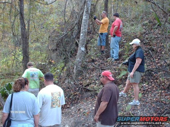 Group of people on a wooded trail, one holding a camera, with a date stamp of 11/28/2008