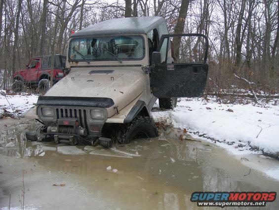 Tan 1991 Jeep Wrangler stuck in icy water with door open