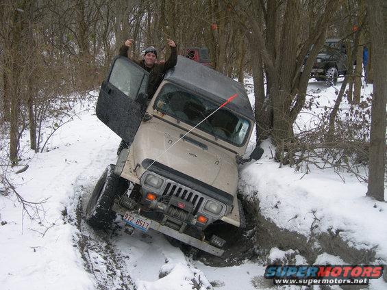 1991 Jeep Wrangler stuck in a snowy ditch with a person giving a thumbs up from the driver's seat. Another Jeep is visible in the background