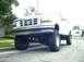1995 Ford Bronco - This lifted 1995 Ford Bronco is shown from a low angle, highlighting its front grille and off-road tires.