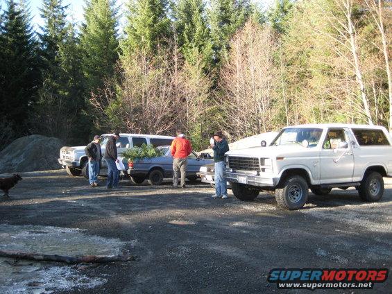 1980 Ford Bronco parked next to a sedan and a van, with people nearby
