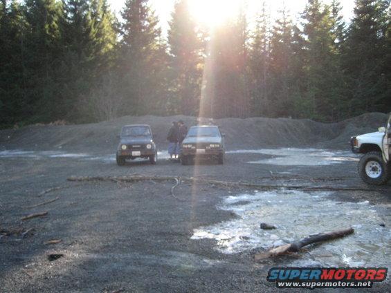 Three SUVs parked on gravel with trees in the background and sun glare