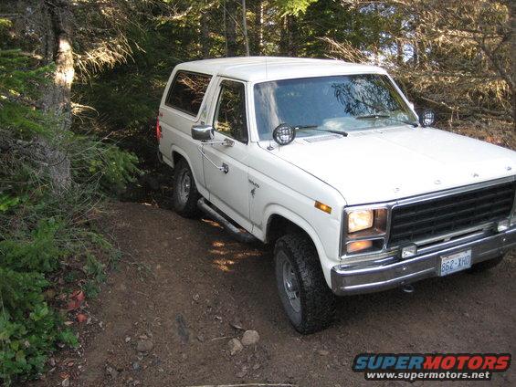 White 1980 Ford Bronco driving on a wooded trail