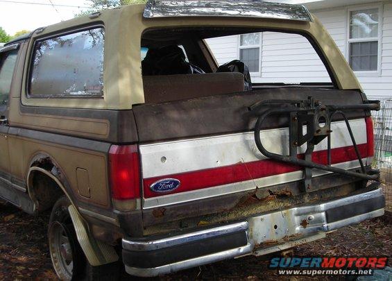 Rear view of a brown 1987 Ford Bronco with a spare tire carrier and chrome bumper