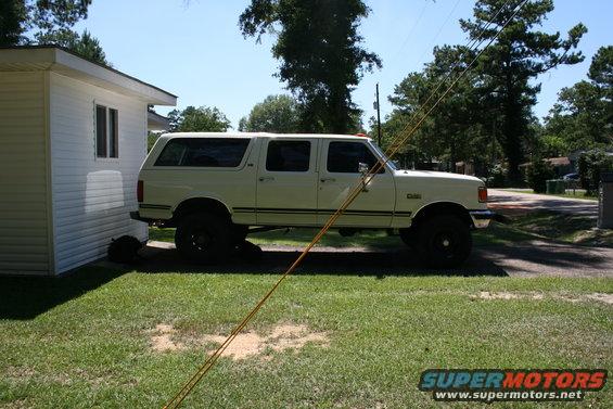 1991 Ford C-350 (Centurion Conversions) extended cab pickup truck parked next to a white building