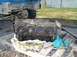 1983 Ford F-150 - A disassembled engine block rests on wooden pallets, with parts of a blue truck visible in the background.