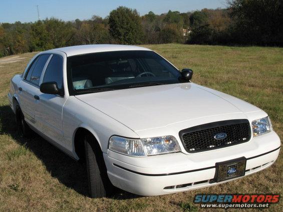 White 2000 Ford Crown Victoria, front grille with Ford emblem, parked on grass