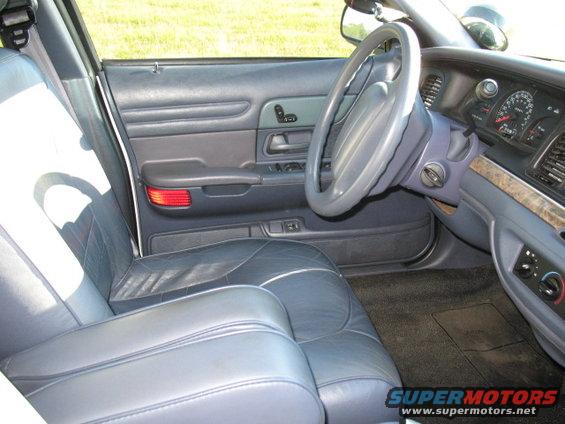 Interior shot of a 2000 Ford Crown Victoria, showing the driver's side door panel, dashboard, steering wheel, and front seats