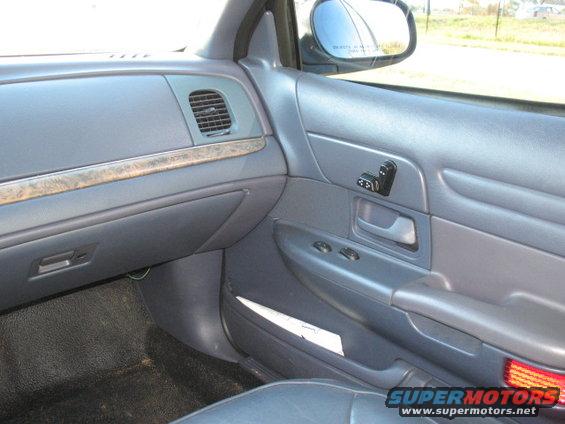 Gray interior of a 2000 Ford Crown Victoria showing the dashboard, door panel, and side mirror