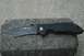 1991 Ford Bronco - A black folding knife with a serrated edge rests on a concrete block.