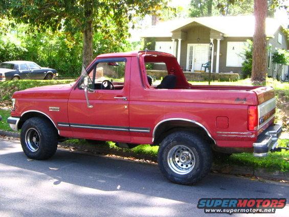 1991 Ford Bronco parked on street, side view. Another car is visible in the background