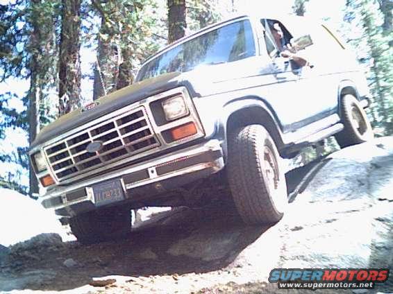 White SUV with prominent grille driving over rocks