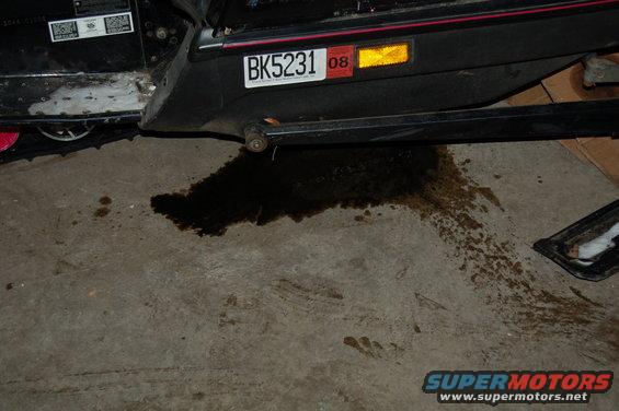 Snowmobile rear section with license plate BK5231 and oil leak on concrete floor