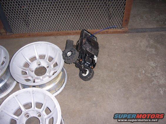 black remote control truck next to a stack of silver car rims