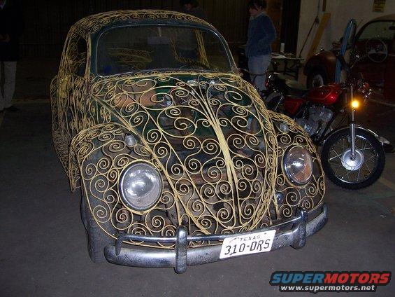Volkswagen Beetle with yellow scrollwork, Texas license plate 310-DRS, parked next to a motorcycle