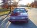 1994 Ford Crown Victoria - A red sedan is parked on a street with trees in the background during autumn.