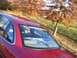 1994 Ford Crown Victoria - The rear of a red sedan is shown with autumn foliage in the background.