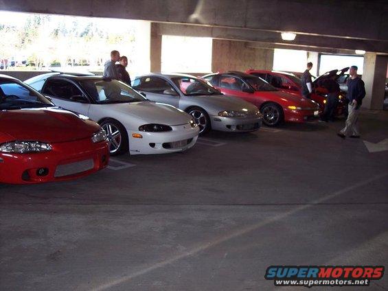 Several Mitsubishi Eclipses parked in a garage, including a red one in front and a white one next to it