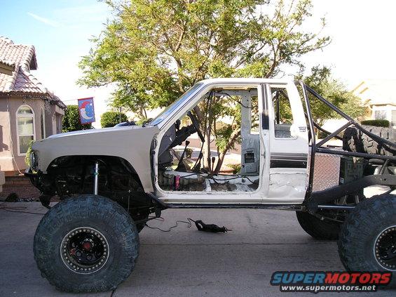 Side view of a modified 1986 Toyota Hilux pickup truck with large tires and no doors