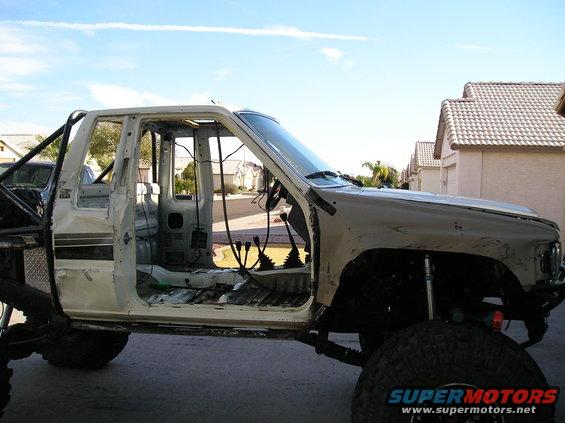 1986 Toyota Hilux chassis with roll cage, doors removed, and interior exposed